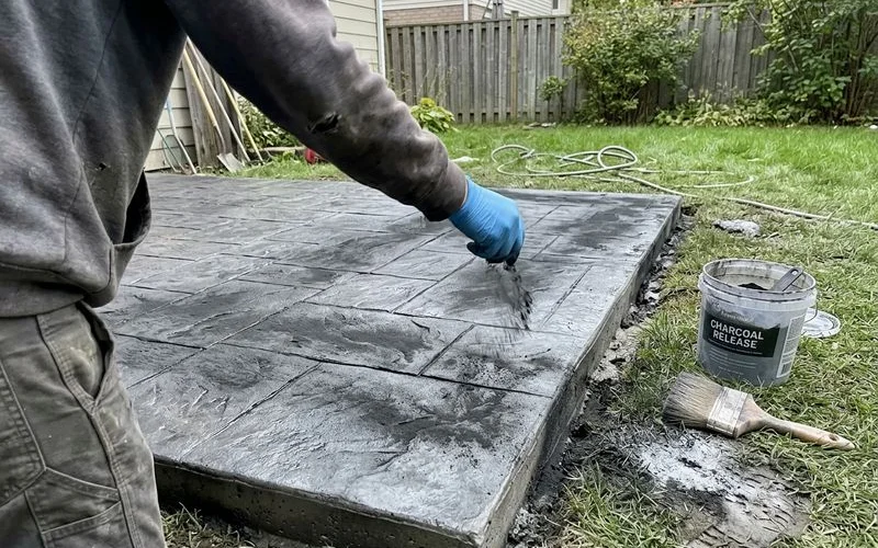 Applying antiquing release powder over a stamped concrete surface