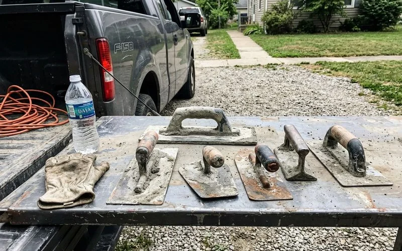 Well-used concrete hand tools laid out on a tailgate after a day on site